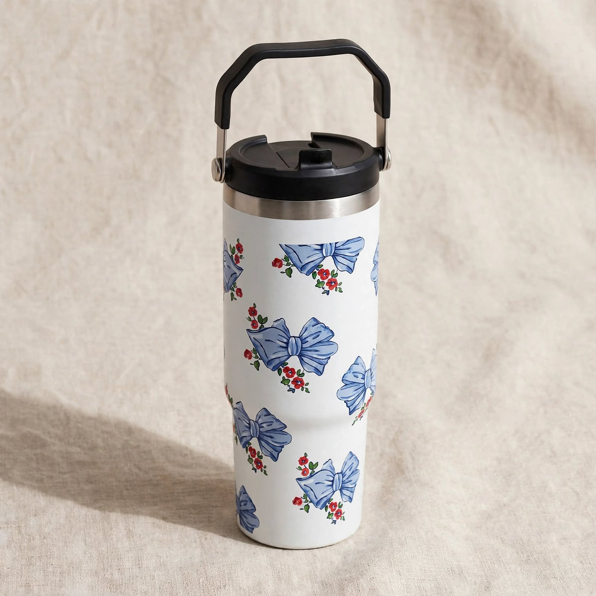 White travel tumbler with blue bows, on linen