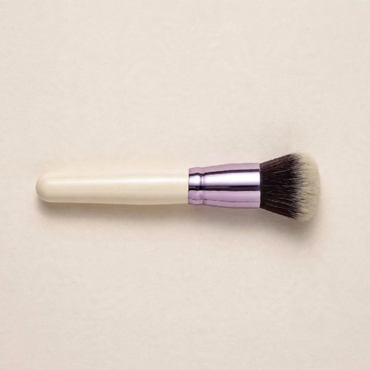 Cream handle powder brush lying flat