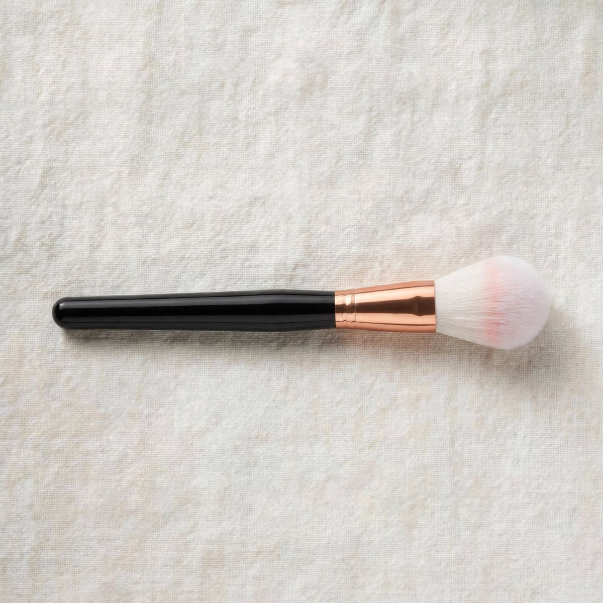 Black handle powder brush lying flat