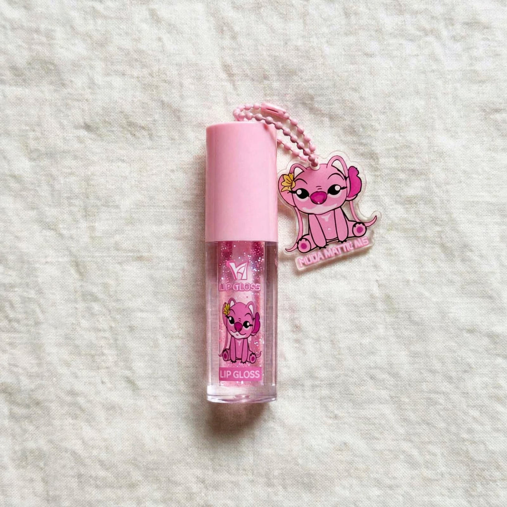 Pink character keychain lip gloss on cream fabric