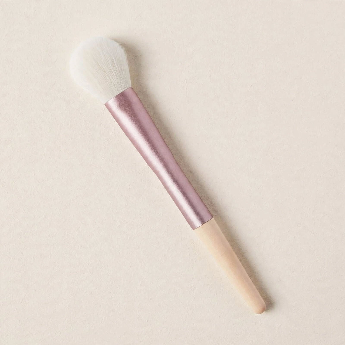 Pink and cream fluffy powder brush lying flat